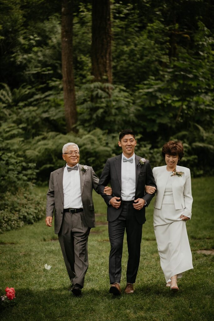 Groom enters the outdoor wedding ceremony with his parents