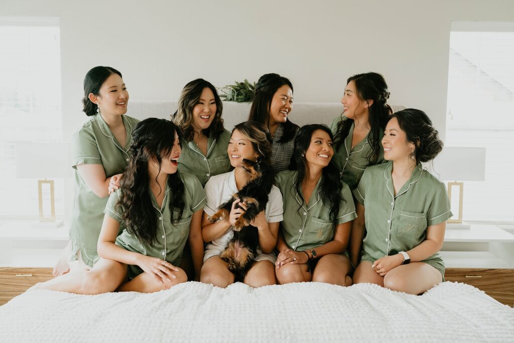 Bride and bridesmaids sitting on the bed while getting ready for Asian wedding