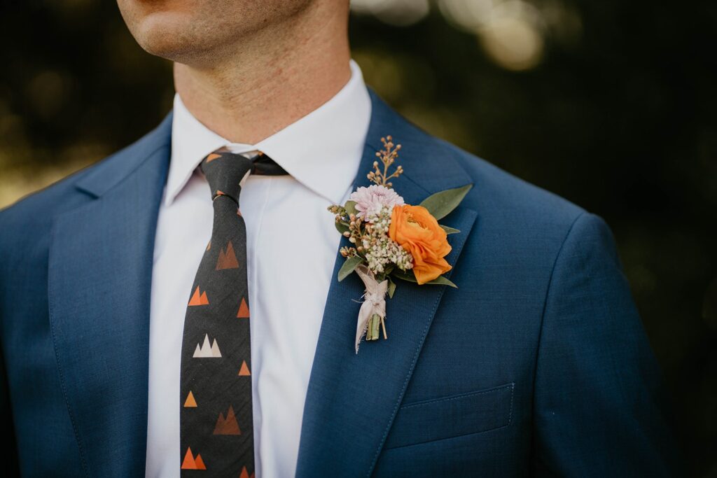 Groom in blue suit with black and orange tie 