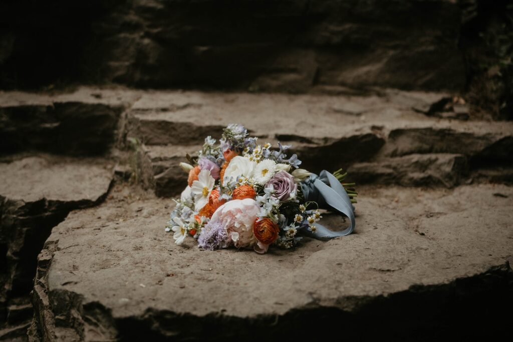 Colorful wedding bouquet with white, purple, and orange flowers