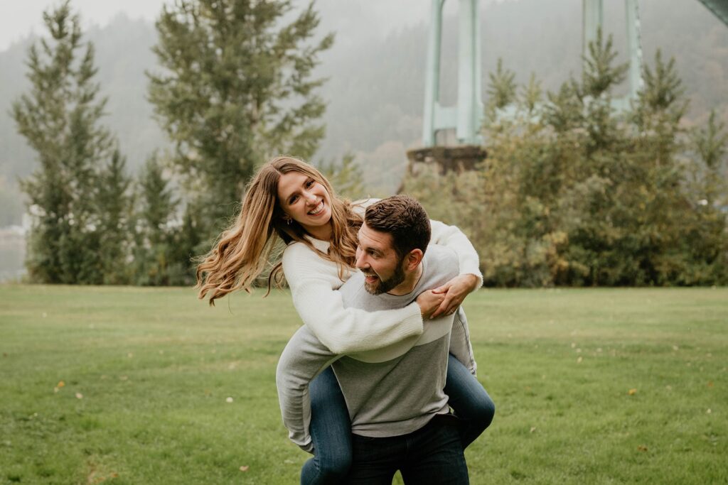 Woman riding on man's back during Cathedral Park, Oregon engagement photos