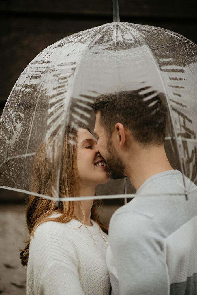 Couple kissing under a clear umbrella during their Portland engagement photos