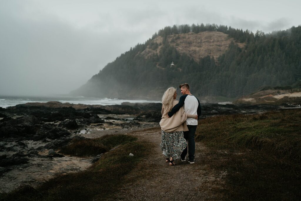 Couple walking down to the ocean during their engagement photos at Cape Perpetua