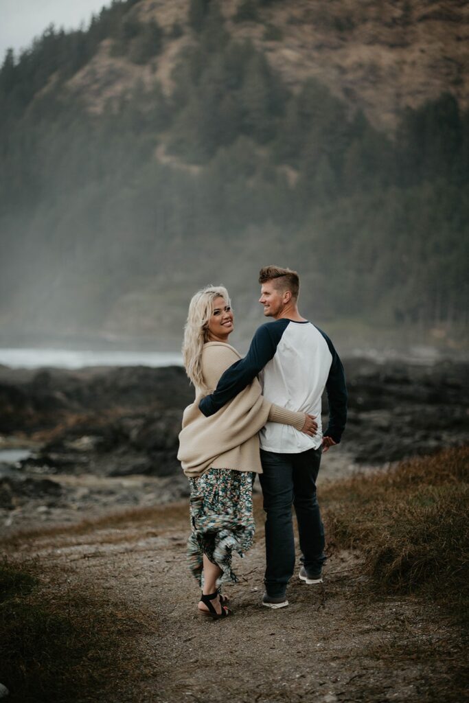 Couple walking down to the ocean during their engagement photos at Cape Perpetua