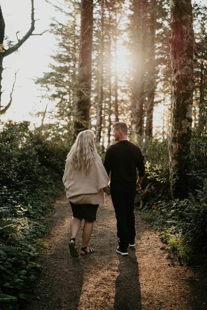 Couple holding hands while walking through the forest at Cape Perpetua