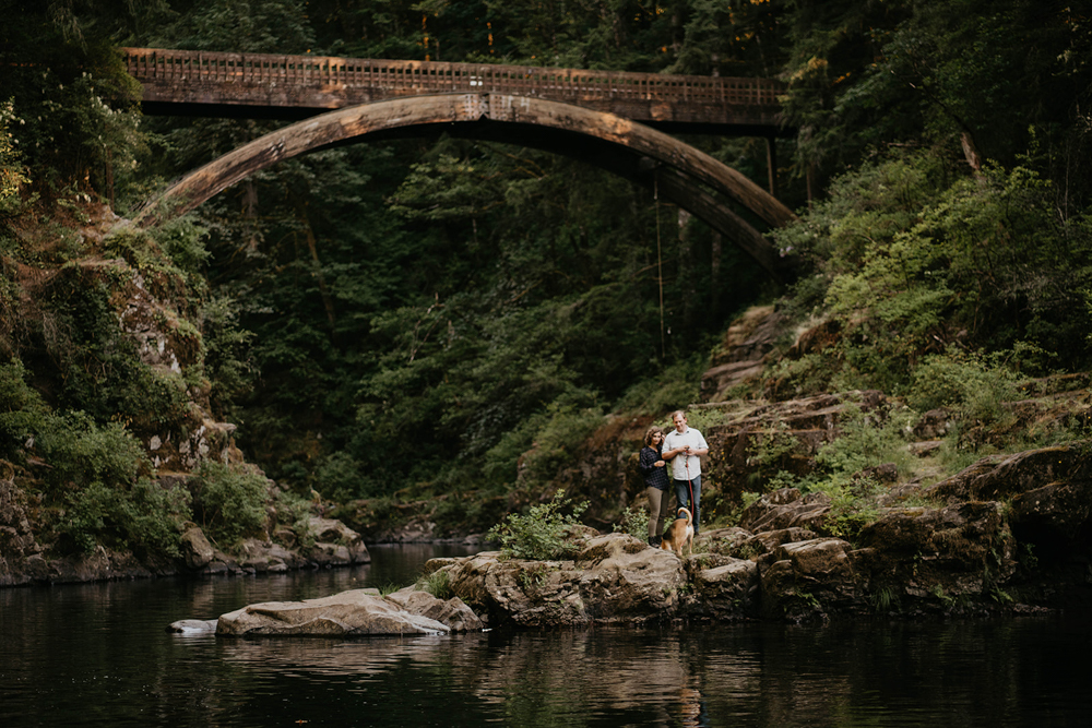 A couple embracing under a three-story arch in a canyon at Moulton Falls.