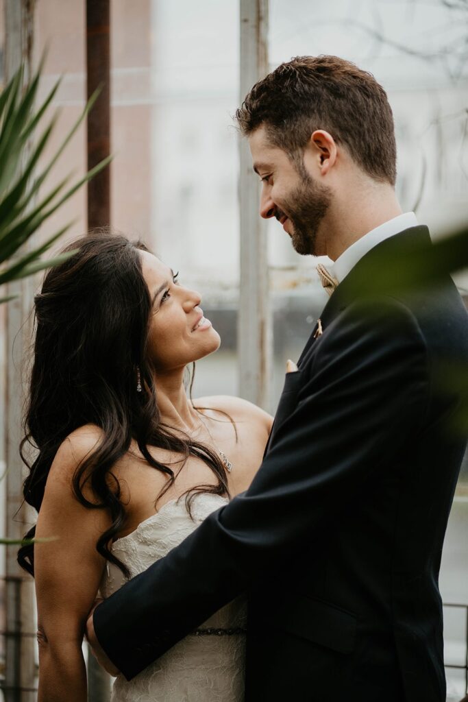 Bride and groom hug and smile at each other during their wedding photos at Pomarius Nursery