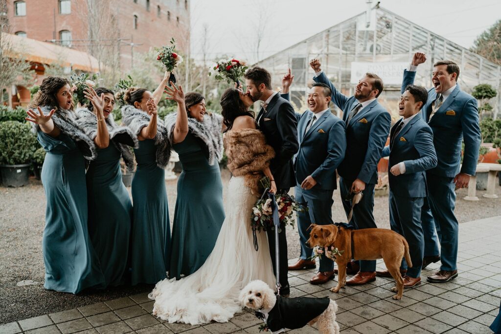 Bride and groom kiss while wedding party cheers at Blockhouse PDX wedding