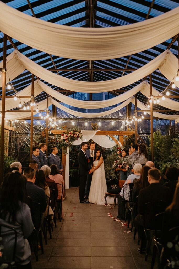 Bride and groom hold hands and look out at their guests during their Blockhouse Portland wedding ceremony