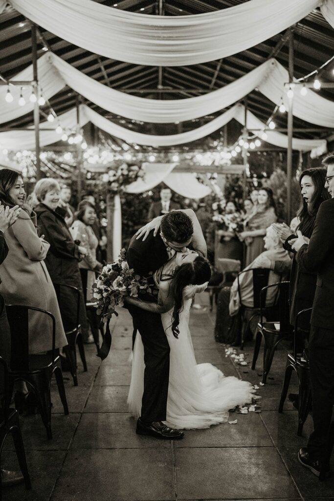 Bride and groom kiss while exiting the aisle at their Blockhouse PDX wedding