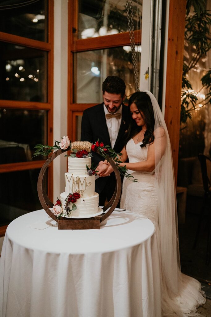 Bride and groom cut three tier wedding cake at Blockhouse wedding in Portland