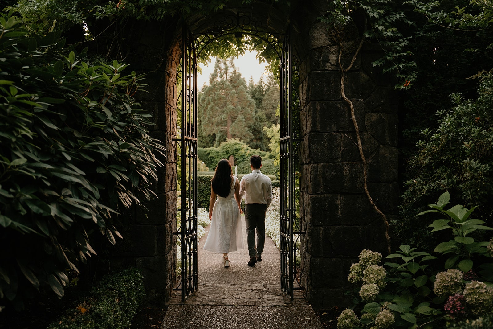 Couple holds hands while walking through the gardes at Chateau de Michellia during their Oregon engagement photo session