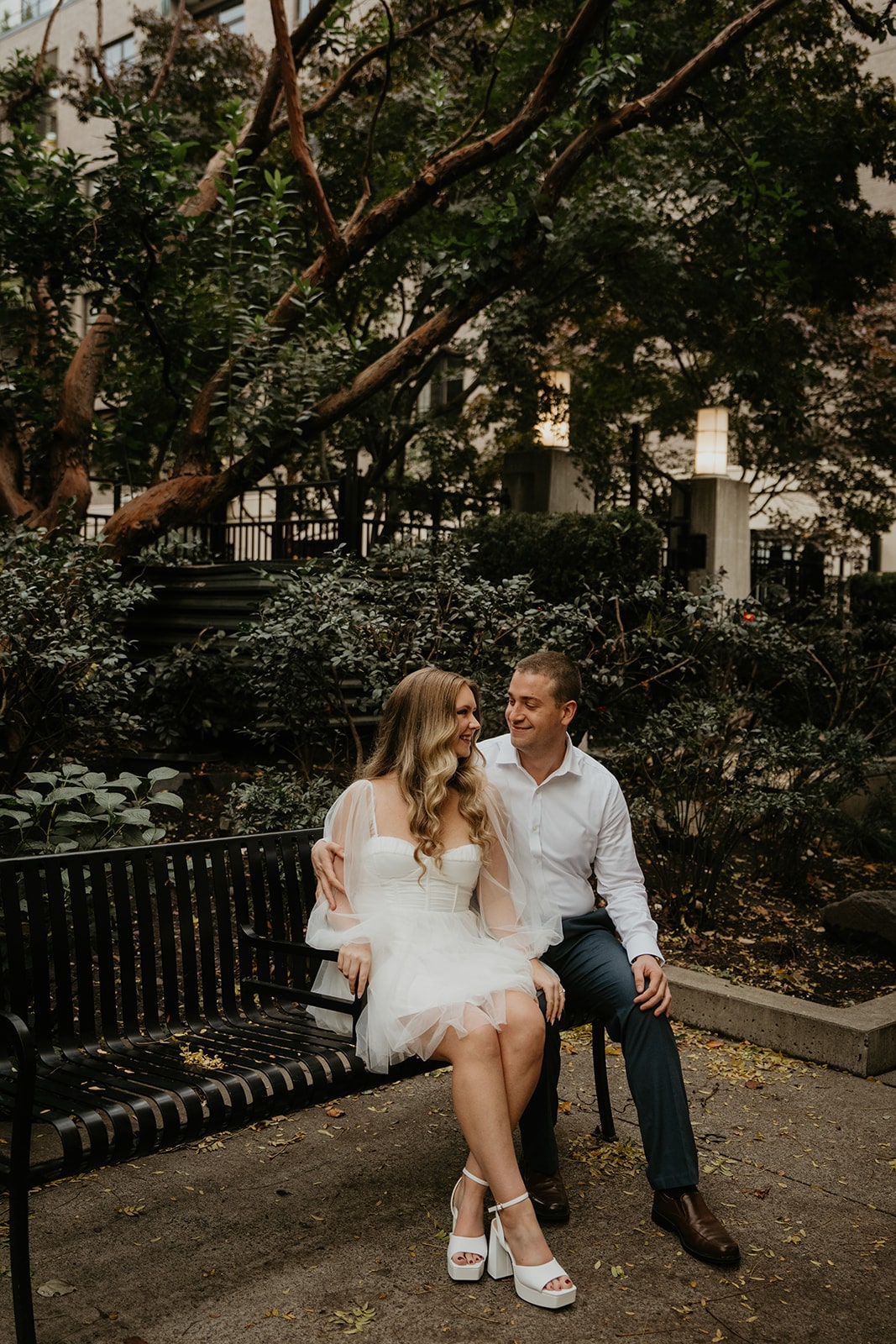 Couple sits on a park bench during their Oregon engagement photo session in downtown Portland