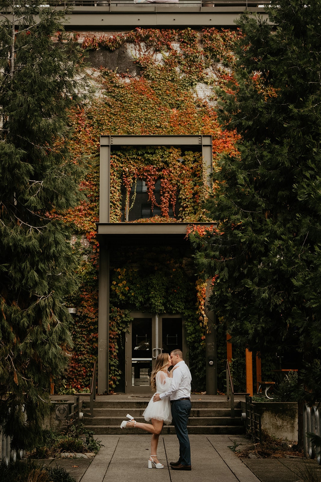 Couple kisses in front of an ivy covered building at their Oregon engagement photo location