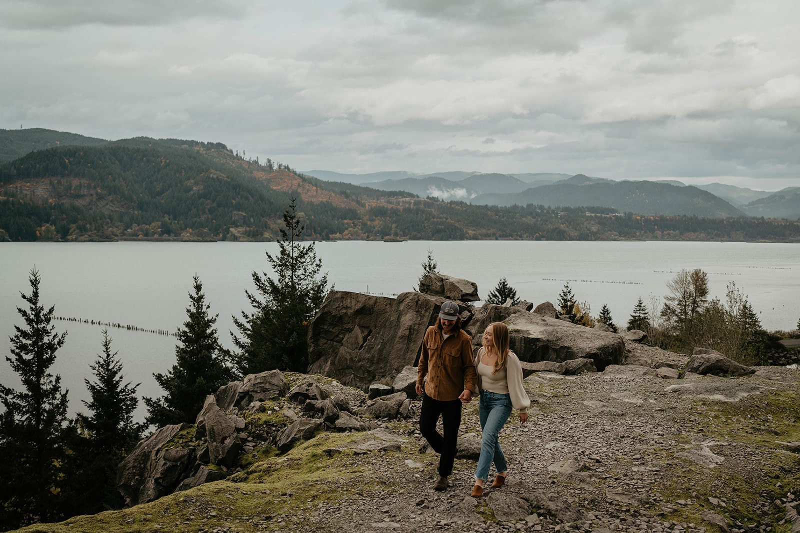 Couple holds hands while walking across Government Cove during their Oregon engagement photo session