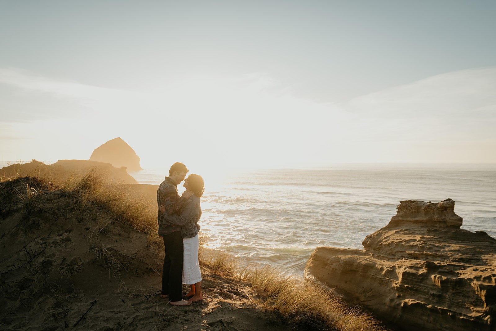 Couple kisses at Cape Kiwanda during their sunset Oregon Coast engagement photo session