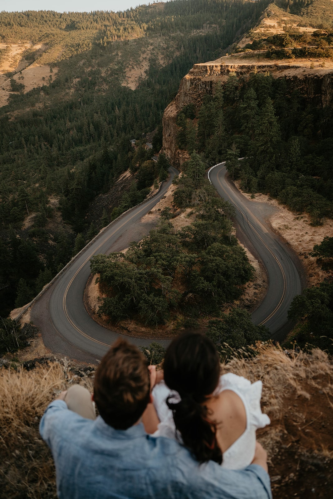 Couple sits at the top of a lookout looking over the Gorge at one of Oregon's best engagement photo locations 