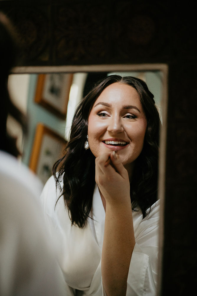 The bride putting on her lipstick while looking in the mirror at an Airbnb in Portland. 