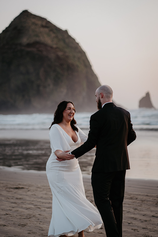 The newlyweds sharing a first dance as the sun sets at Cannon beach with Haystack Rock in the background. 