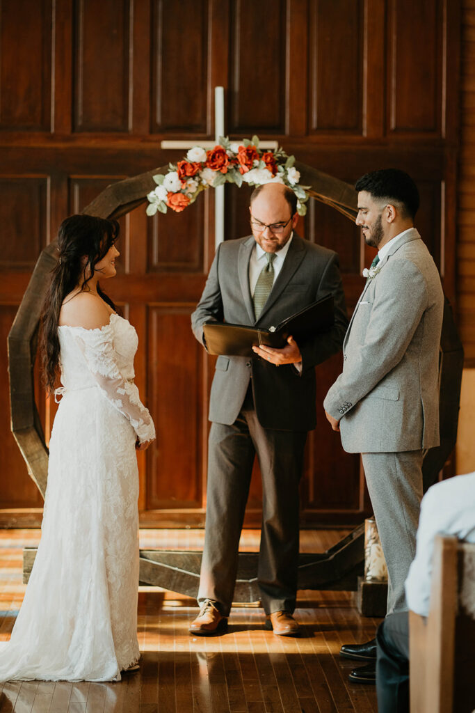 The bride and groom standing at the alter with the officiant between them. 