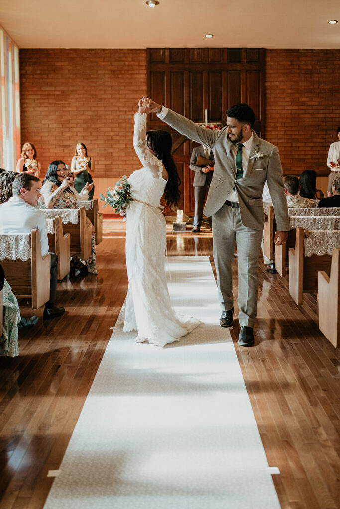 The groom twirling the bride while they walk down the isle. 