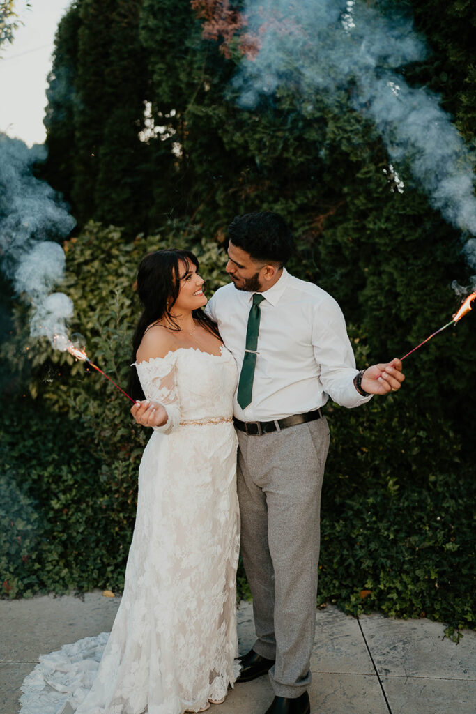 The bride and groom looking lovingly into each other's eyes while holding sparklers. 