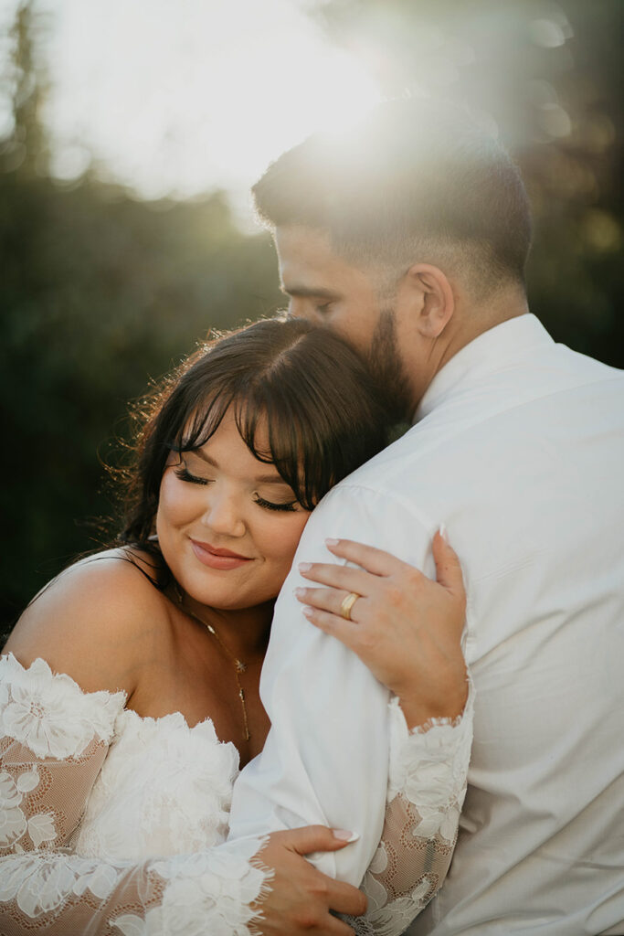 The bride and groom backlit and hugging. 