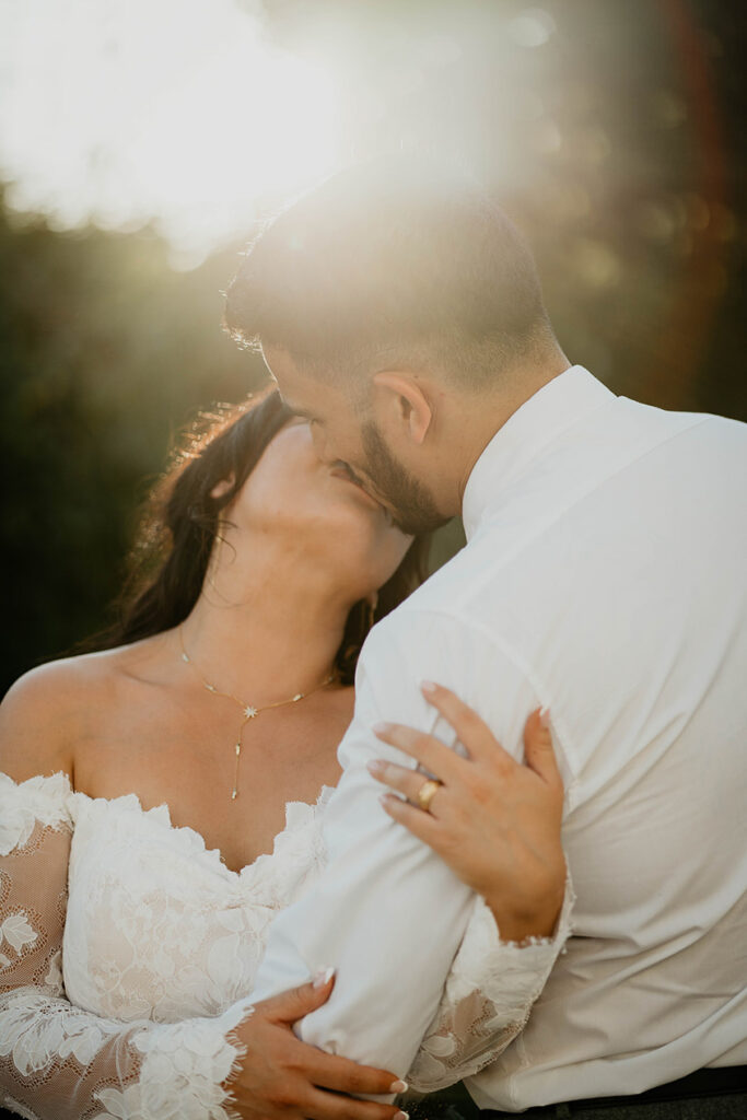 The bride and groom backlit and kissing. 