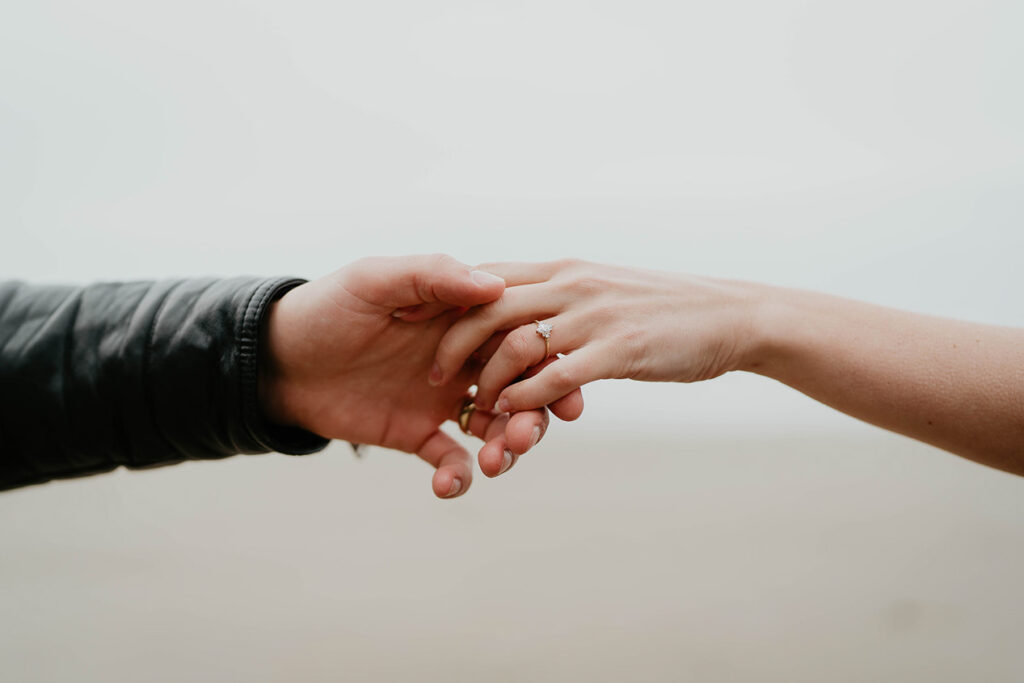 A closeup on the hands of a couple holding hands. 