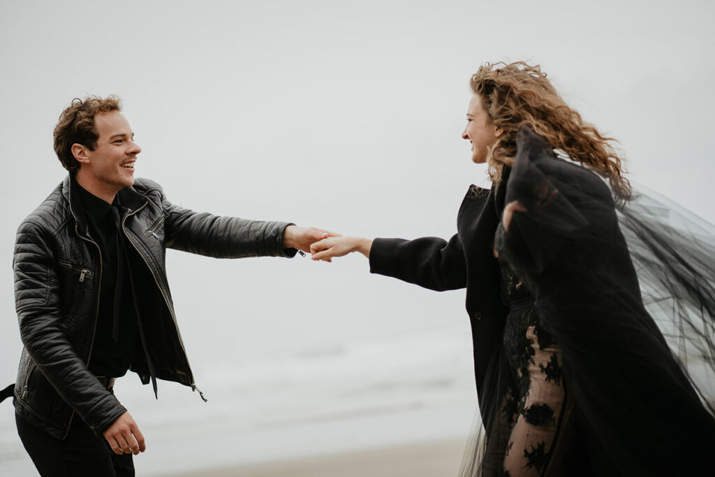 A couple holding hands and looking lovingly into each other's eyes by the beach. 