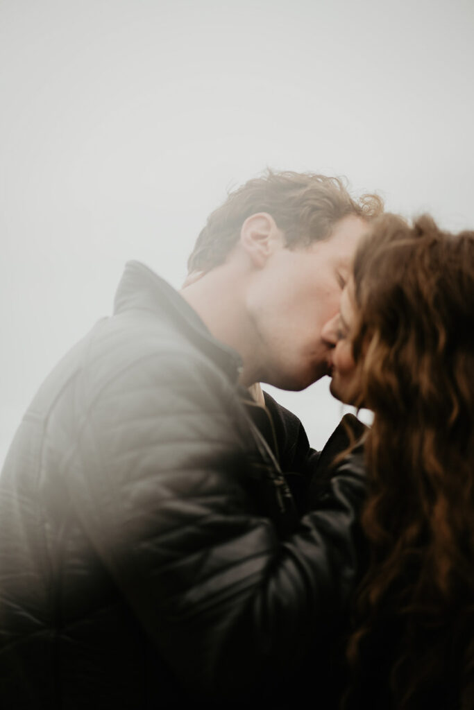 A couple dressed in all black kissing. 