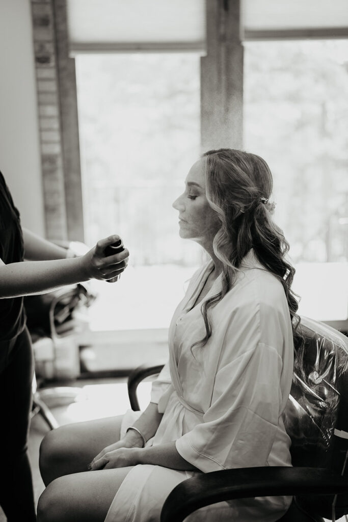 The bride getting her hair sprayed by a stylist. 