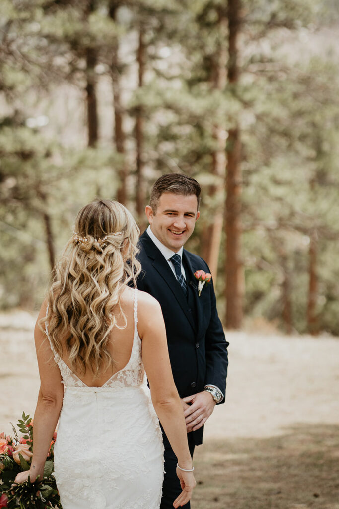 The groom smiling after turning around and seeing the bride for the first time.