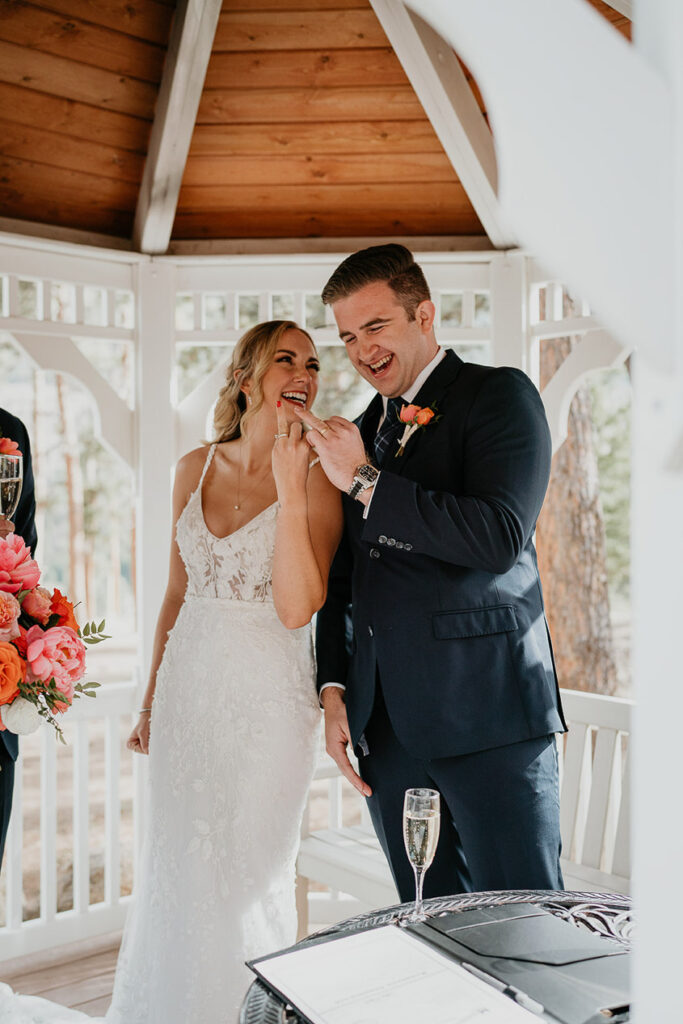 The bride and groom standing in a gazebo showing off their wedding rings. 