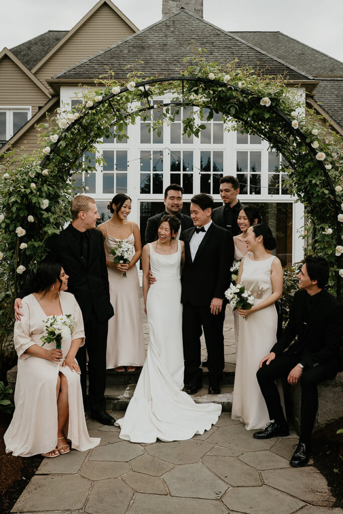 Judith and Joshua's wedding party under a green, flowery arch. 