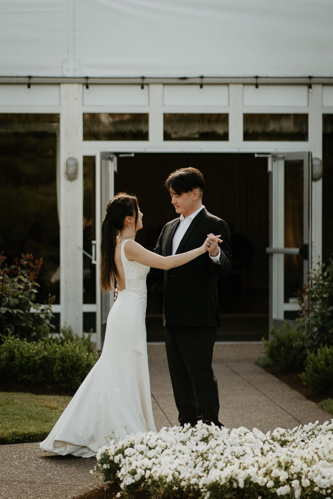 Judith and Joshua dancing in a grassy and flowery courtyard. 