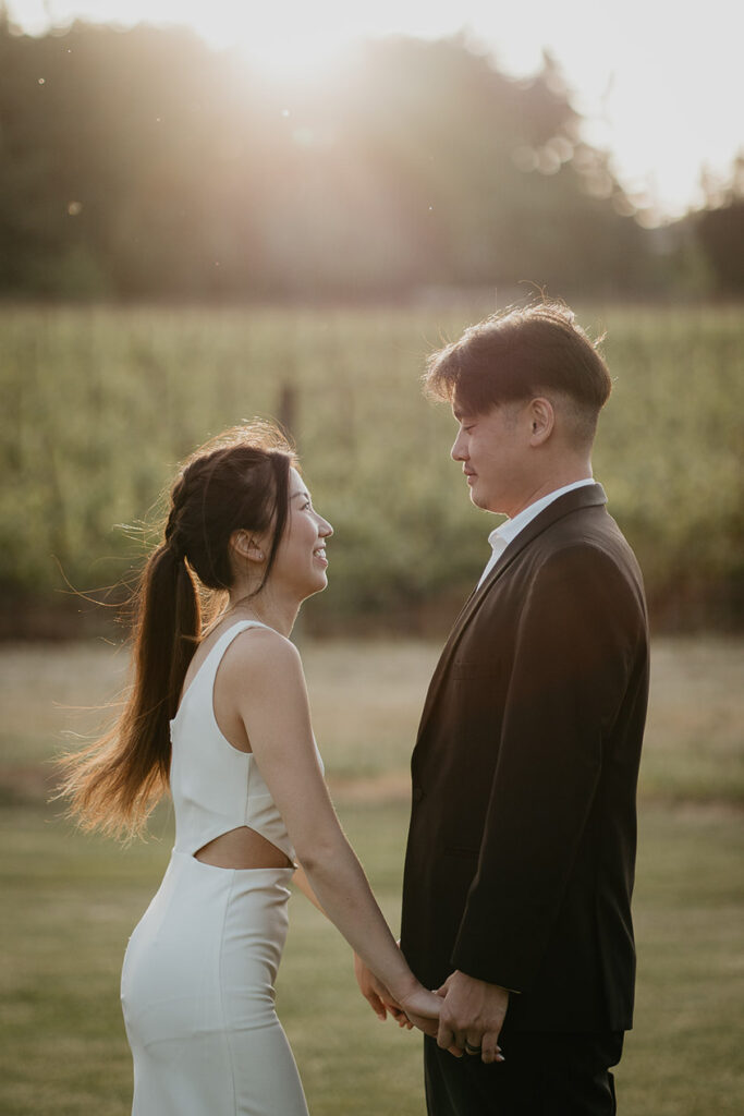 Joshua and Judith holding hands with a vineyard in the background. 