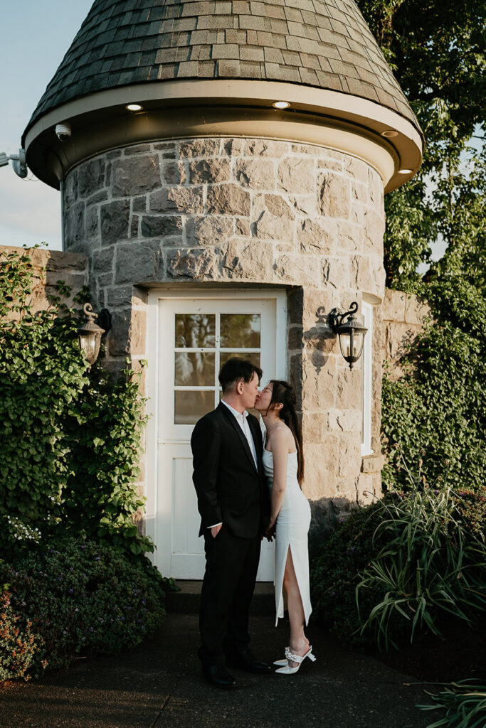 Joshua and Judith kissing in front of a stone building. 