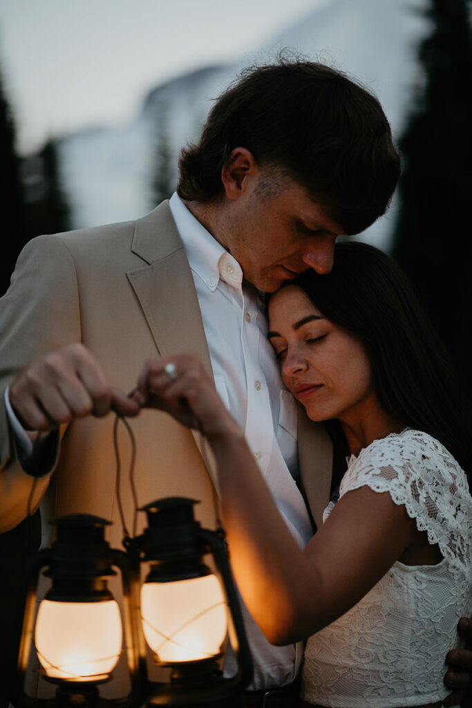 The couple hugging and holding lanterns in the blue light. 