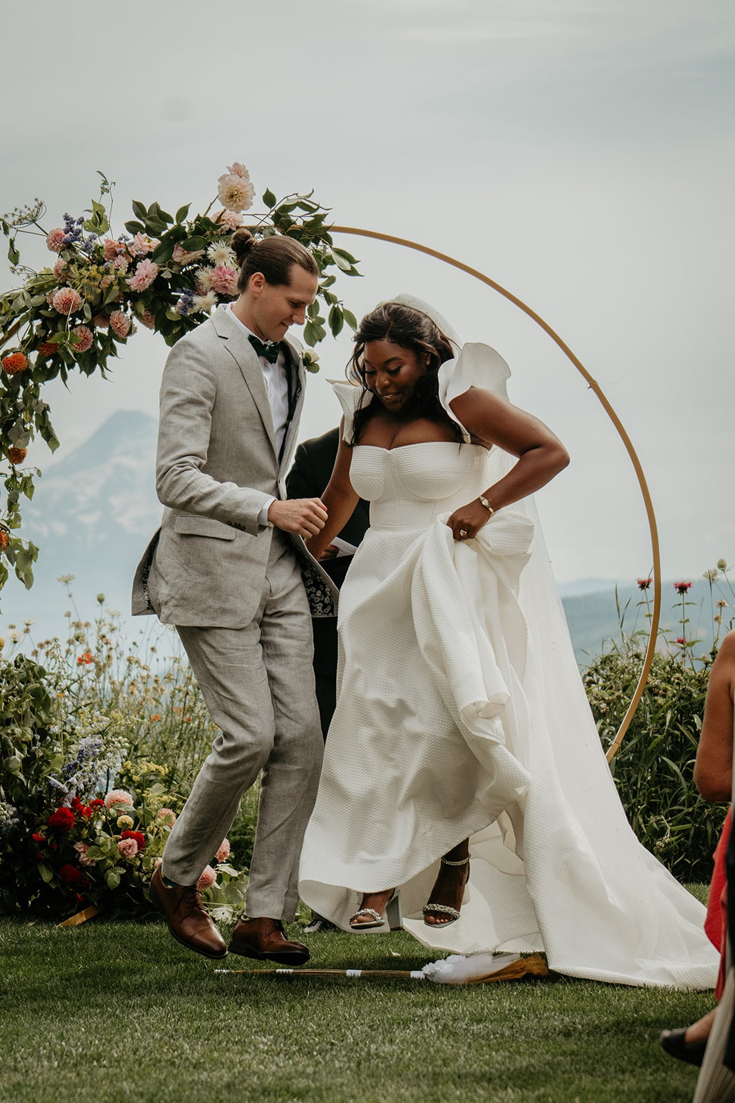 Bride and groom jump over a broom at their winery wedding ceremony in Washington