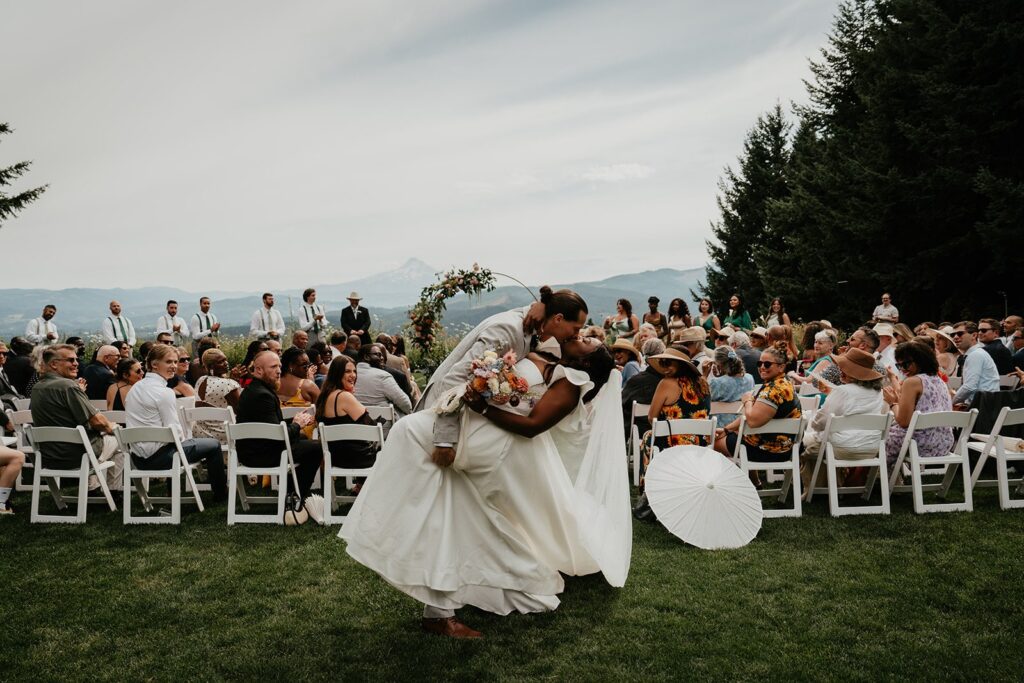 Groom dips bride for a kiss after winery wedding ceremony at Gorge Crest Vineyards