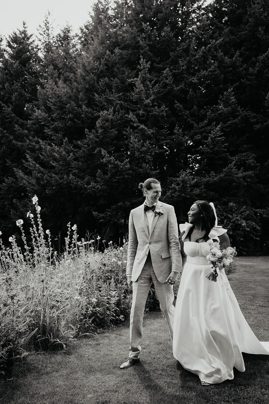 Bride and groom hold hands while walking through the fields at Gorge Crest Vineyards wedding