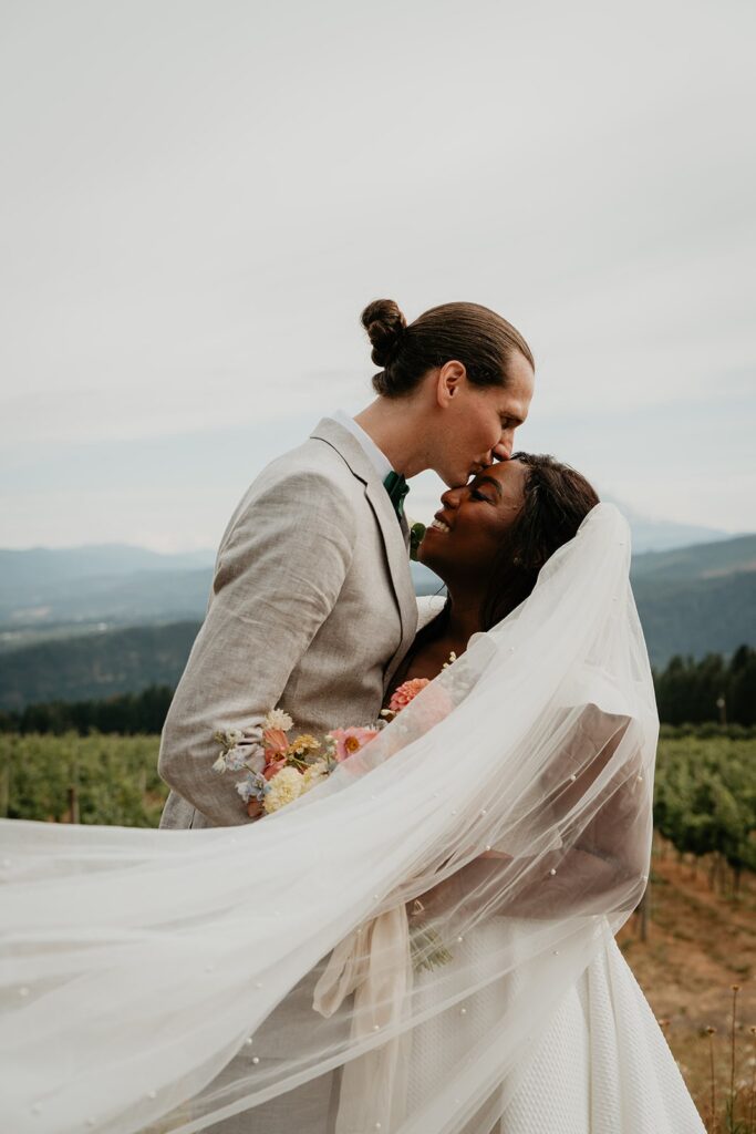 Groom kisses bride on the forehead during Gorge Crest Vineyards winery wedding