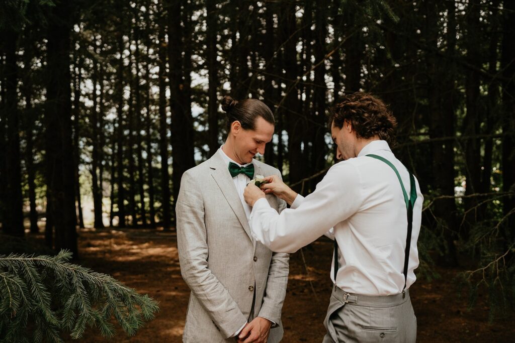 Groomsman helping groom pin boutonniere on his jacket