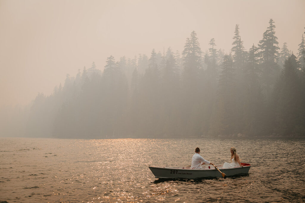 The groom-to-be rowing a boat with his fiancé as on the smokey Lost Lake. 