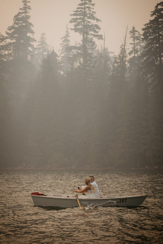 The groom-to-be rowing a boat with his fiancé as on the smokey Lost Lake. 