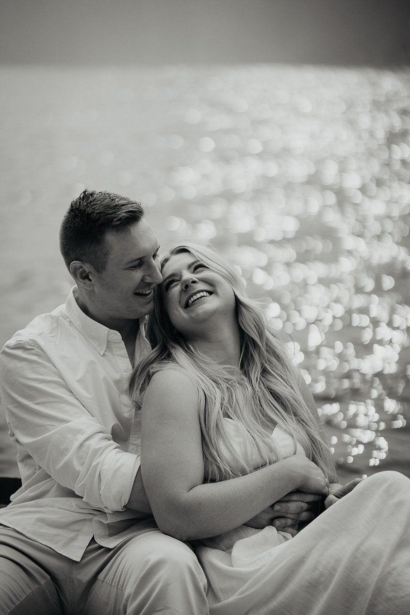 A couple hugging on a row boat on Lost Lake, with smoke and pine trees in the background. 