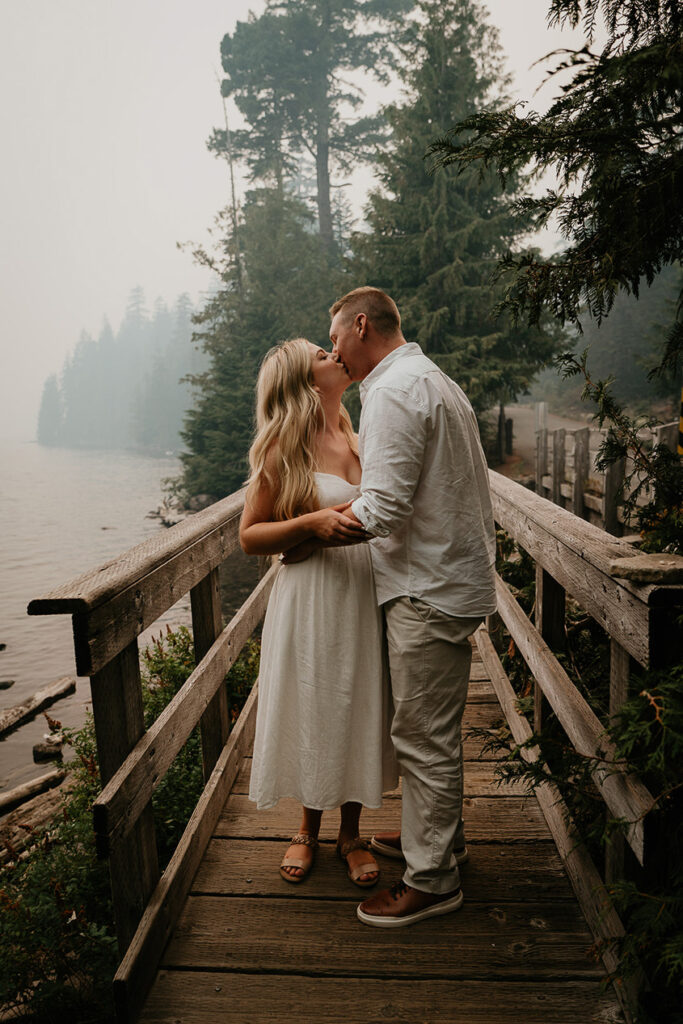 A couple kissing on a bridge. 