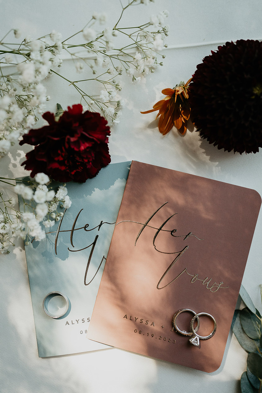 Paper vows, rings, and flowers on a white table. 