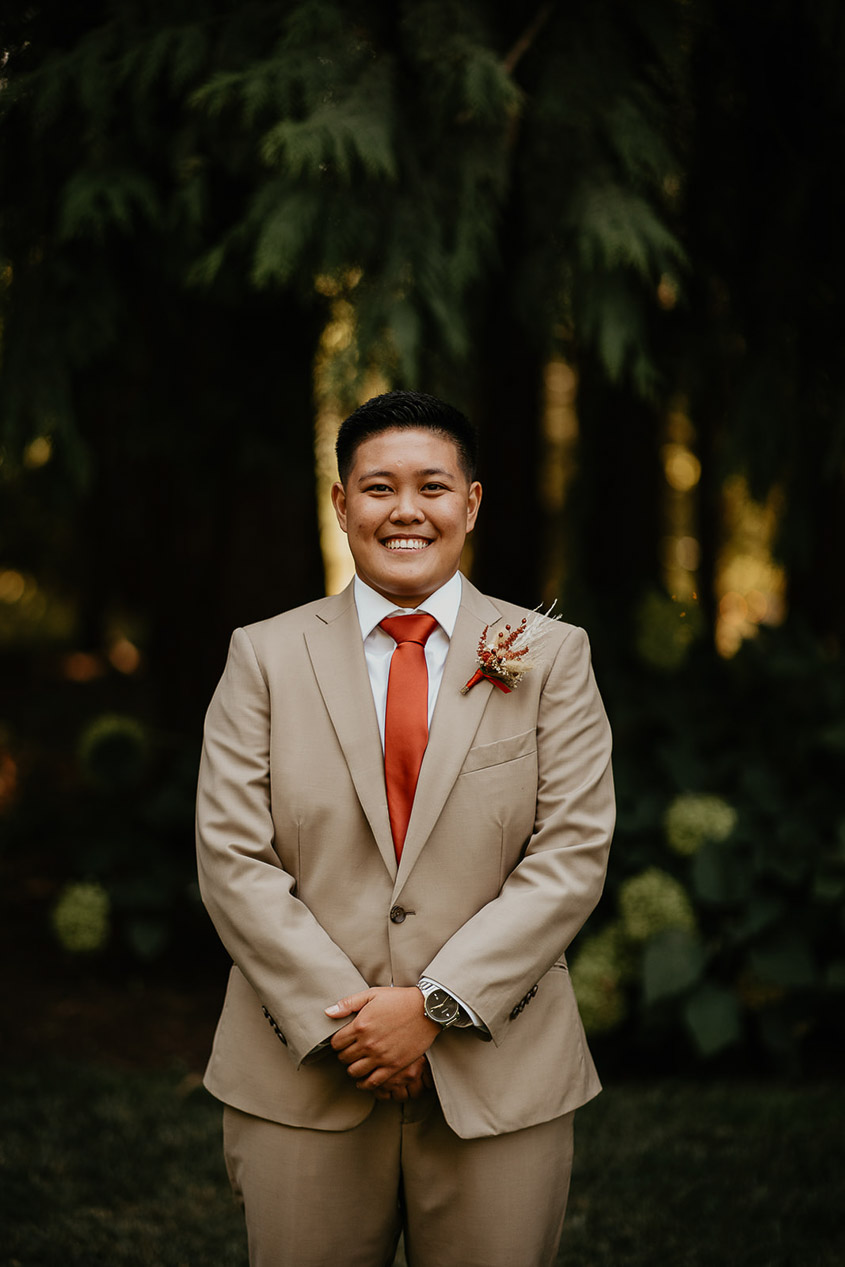 One of the brides in a suit posing and smiling for the camera. 